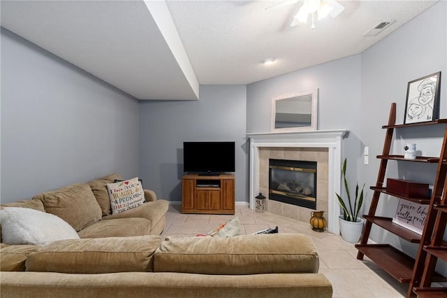 living area featuring light tile patterned floors, visible vents, ceiling fan, and a fireplace