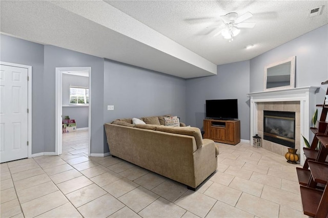 living area featuring visible vents, light tile patterned floors, a ceiling fan, and baseboards