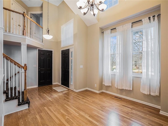 entrance foyer with hardwood / wood-style floors, a notable chandelier, and a high ceiling