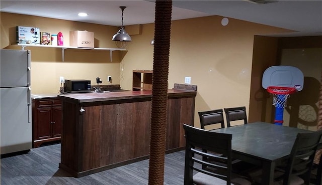 kitchen with fridge, decorative light fixtures, dark hardwood / wood-style flooring, and a breakfast bar area