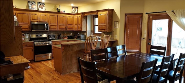 kitchen featuring stainless steel appliances, tile counters, light hardwood / wood-style floors, and decorative backsplash