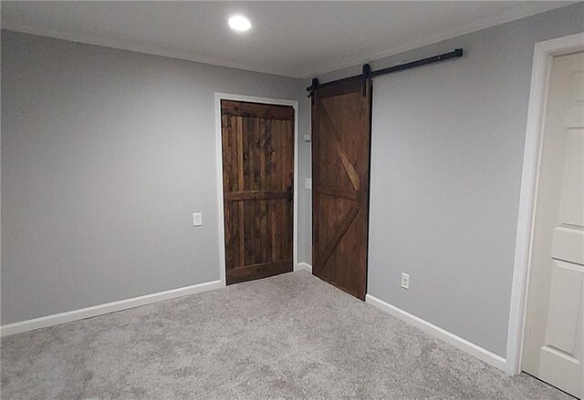 unfurnished bedroom featuring a barn door and carpet