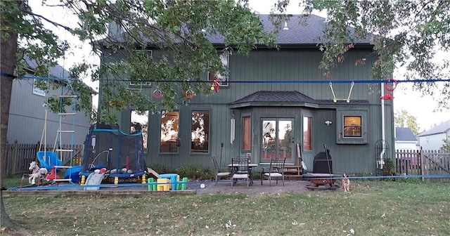 rear view of house with a trampoline and a lawn