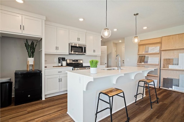 kitchen with white cabinetry, appliances with stainless steel finishes, sink, and an island with sink