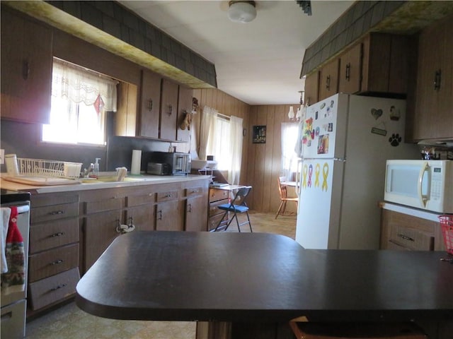 kitchen featuring white appliances and wood walls