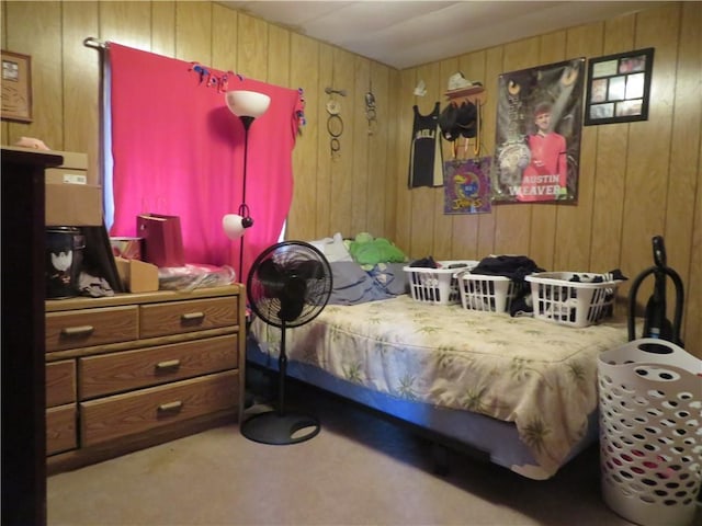 bedroom with light colored carpet and wooden walls