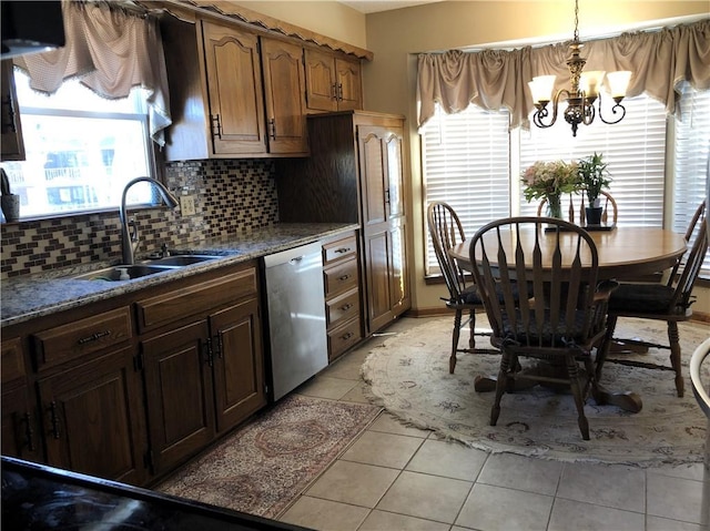 kitchen featuring pendant lighting, dishwasher, sink, decorative backsplash, and light tile patterned floors