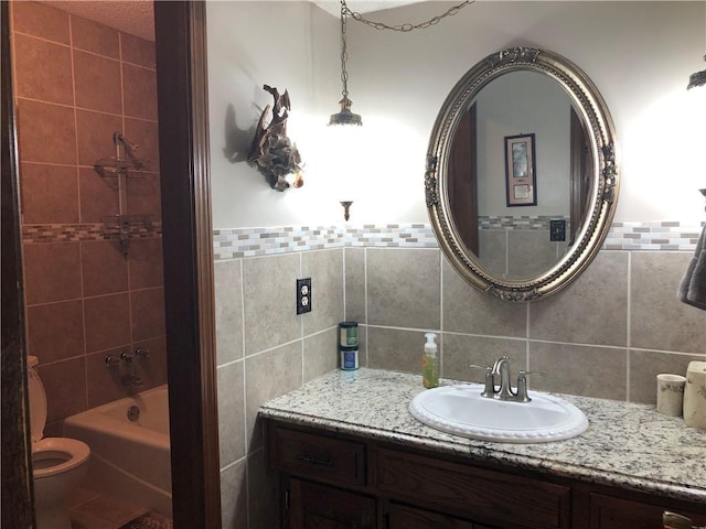 bathroom with tile walls, vanity, and tiled shower / bath