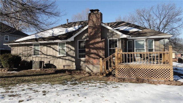 snow covered house with central AC and a deck