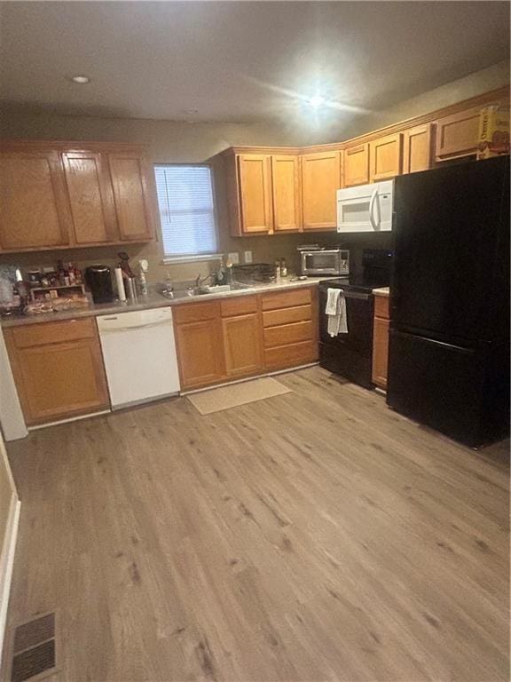 kitchen with sink, white appliances, and light wood-type flooring