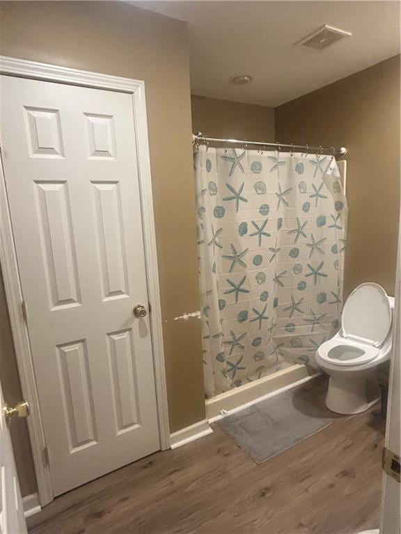 bathroom featuring wood-type flooring, toilet, and walk in shower