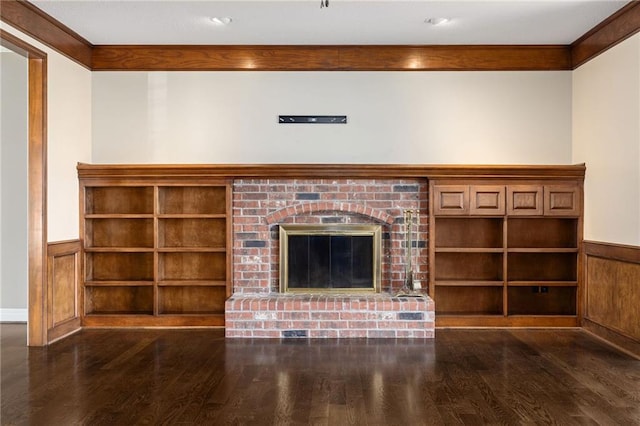 unfurnished living room featuring a fireplace, crown molding, wood finished floors, and wainscoting