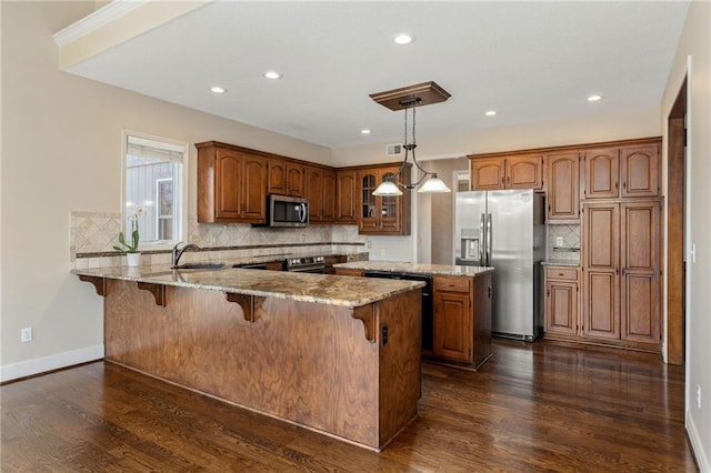 kitchen with a sink, a peninsula, brown cabinets, and stainless steel appliances