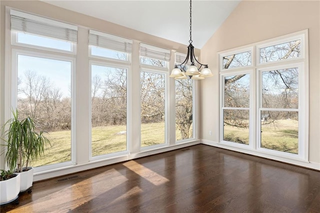 unfurnished dining area with dark wood finished floors, vaulted ceiling, a notable chandelier, and visible vents