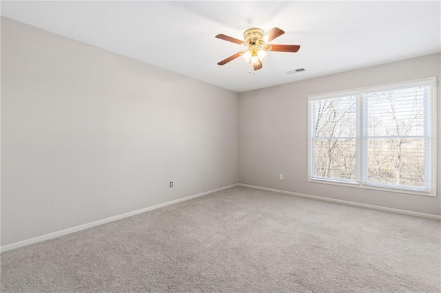 carpeted spare room with a ceiling fan, visible vents, and baseboards