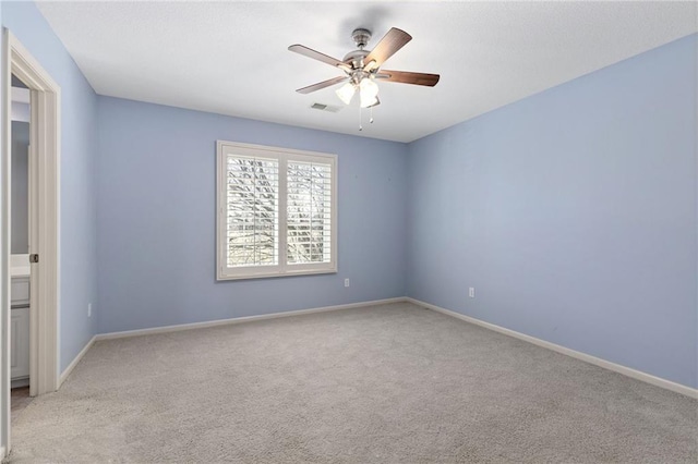 empty room featuring light colored carpet, a ceiling fan, visible vents, and baseboards