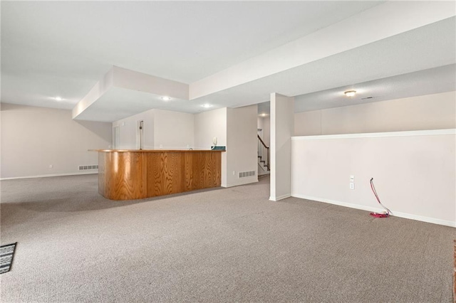 finished basement featuring baseboards, visible vents, wet bar, and carpet