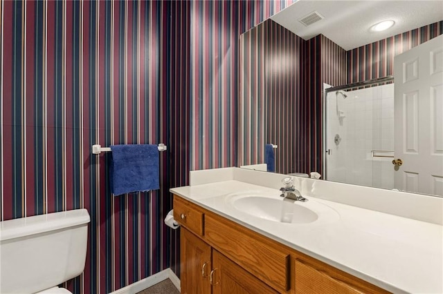 bathroom featuring vanity, visible vents, tiled shower, wallpapered walls, and toilet