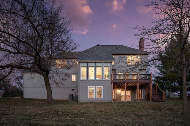 back of house at dusk with a wooden deck, a yard, central AC, a chimney, and stairs