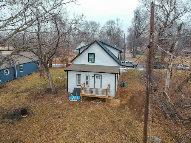 rear view of house featuring central AC unit, covered porch, and a lawn