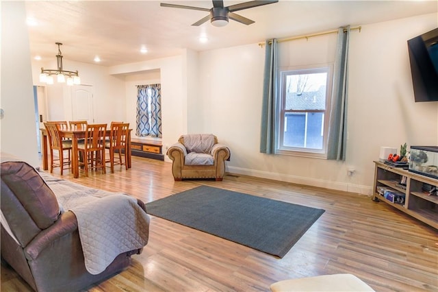 living room with ceiling fan with notable chandelier and light wood-type flooring