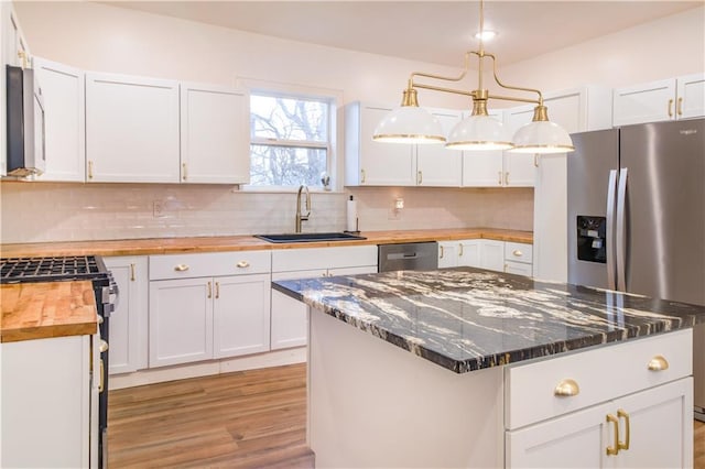 kitchen featuring sink, wooden counters, hanging light fixtures, a center island, and white cabinets