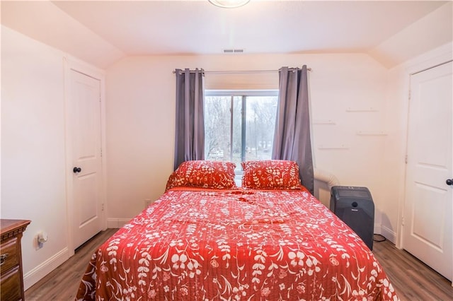 bedroom with dark wood-type flooring and lofted ceiling