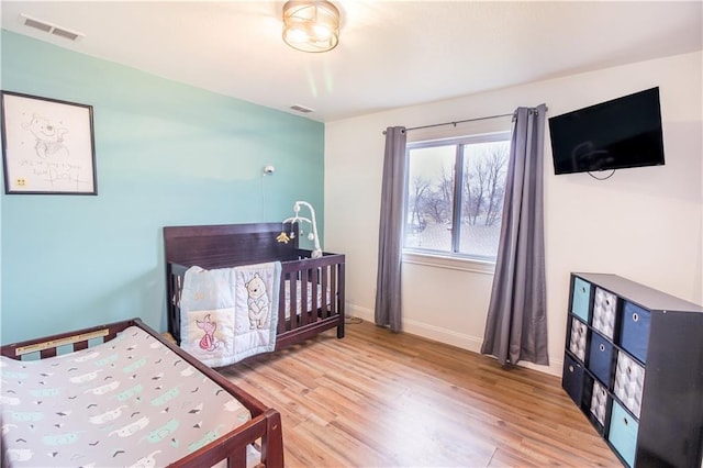 bedroom with a crib and wood-type flooring