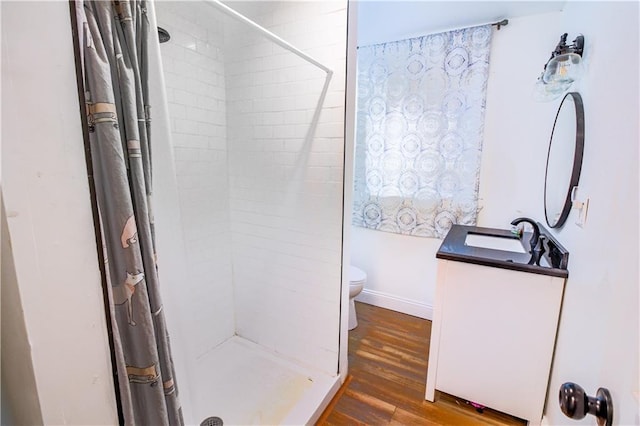 bathroom featuring wood-type flooring, curtained shower, vanity, and toilet