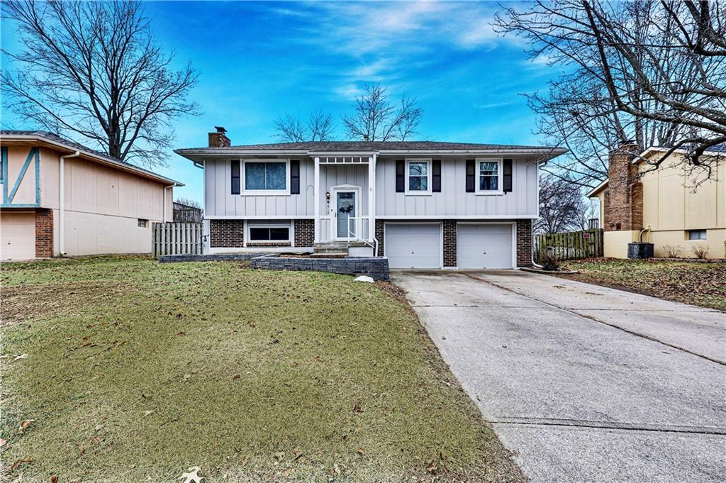 raised ranch with a garage, a front lawn, and central air condition unit