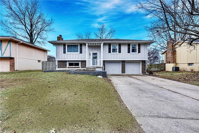 raised ranch with a garage, a front lawn, and central air condition unit