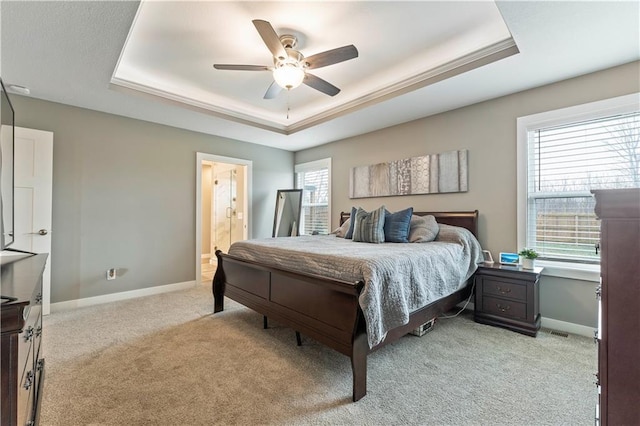 carpeted bedroom with ceiling fan, ensuite bath, and a tray ceiling