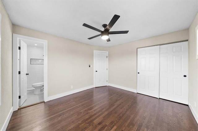 unfurnished bedroom featuring ensuite bathroom, dark hardwood / wood-style floors, ceiling fan, and a closet