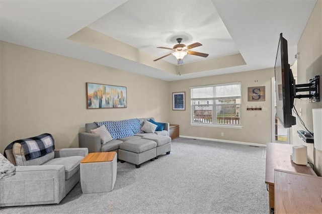 living room with ceiling fan, a tray ceiling, and carpet flooring