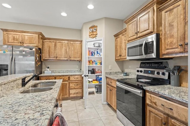 kitchen featuring appliances with stainless steel finishes, light stone countertops, sink, and light tile patterned floors