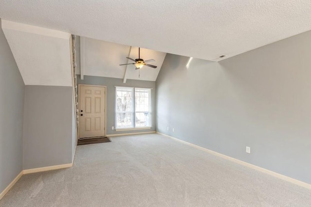 unfurnished living room featuring light carpet, ceiling fan, vaulted ceiling, and a textured ceiling