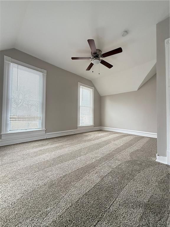 additional living space with carpet, vaulted ceiling, baseboards, and ceiling fan