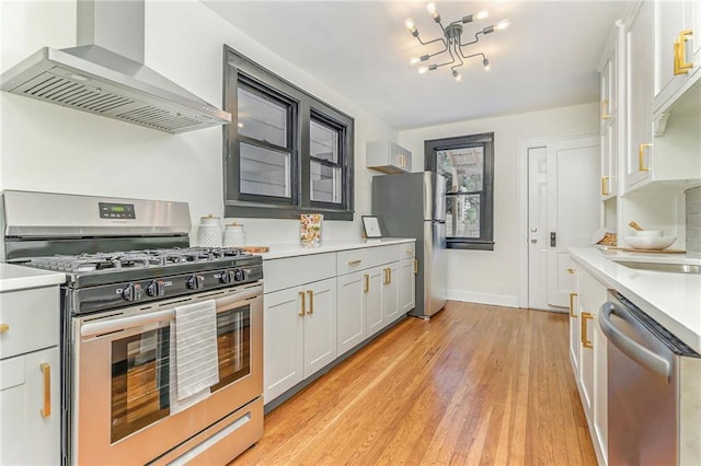 kitchen with sink, light hardwood / wood-style flooring, stainless steel appliances, white cabinets, and wall chimney exhaust hood