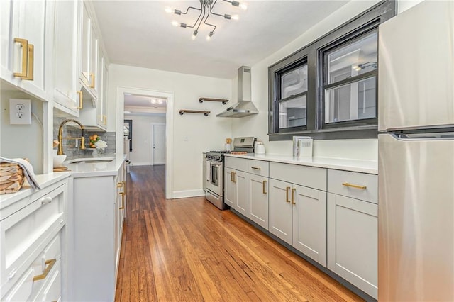 kitchen featuring wall chimney exhaust hood, sink, gray cabinets, stainless steel appliances, and light hardwood / wood-style floors