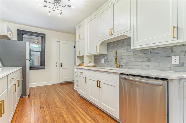 kitchen with sink, light hardwood / wood-style flooring, appliances with stainless steel finishes, tasteful backsplash, and white cabinets