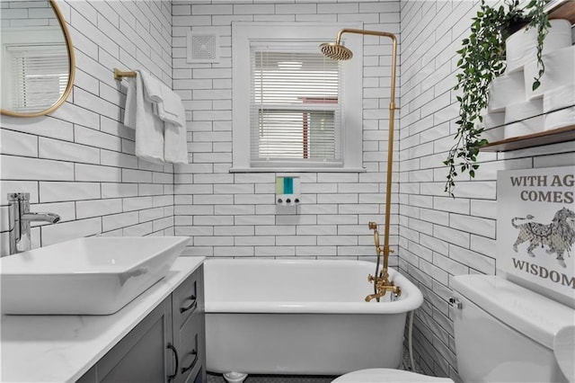 bathroom featuring tasteful backsplash, a tub, tile walls, vanity, and toilet