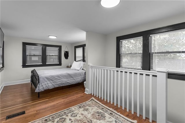 bedroom with hardwood / wood-style floors and multiple windows