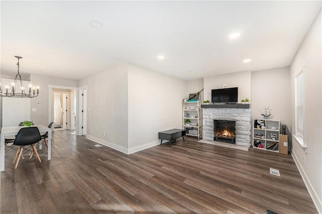 living room with a notable chandelier, a fireplace, and dark hardwood / wood-style floors