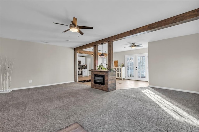 unfurnished living room featuring beamed ceiling, ceiling fan, carpet flooring, and french doors