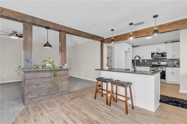 kitchen featuring appliances with stainless steel finishes, decorative light fixtures, and white cabinets