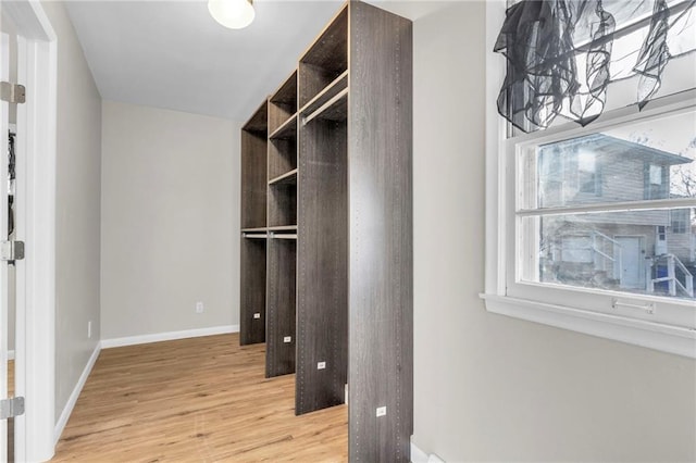 walk in closet with light hardwood / wood-style floors