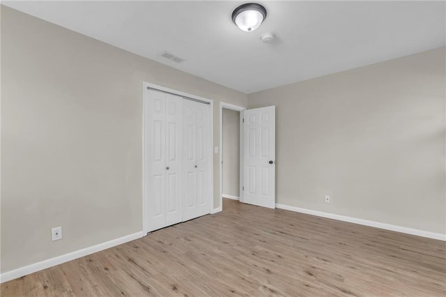 unfurnished bedroom with light wood-type flooring and a closet