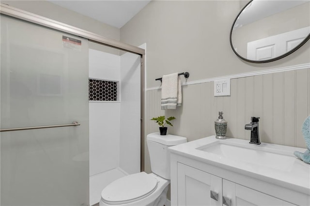 bathroom featuring vanity, a shower with door, and toilet