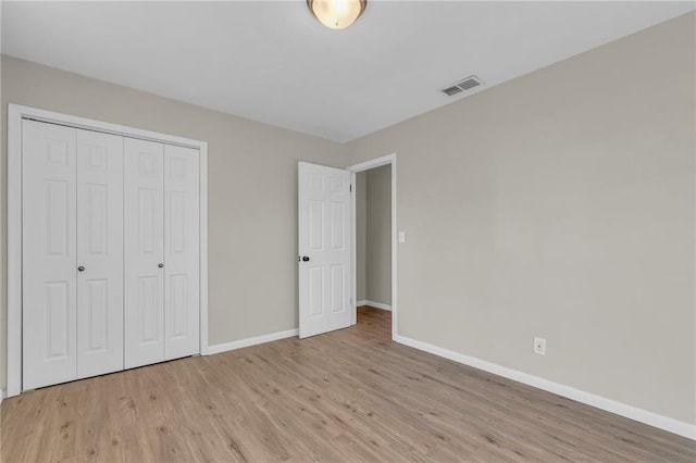 unfurnished bedroom with a closet and light wood-type flooring