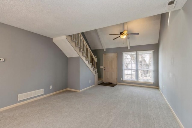 unfurnished living room featuring light carpet, ceiling fan, vaulted ceiling, and a textured ceiling